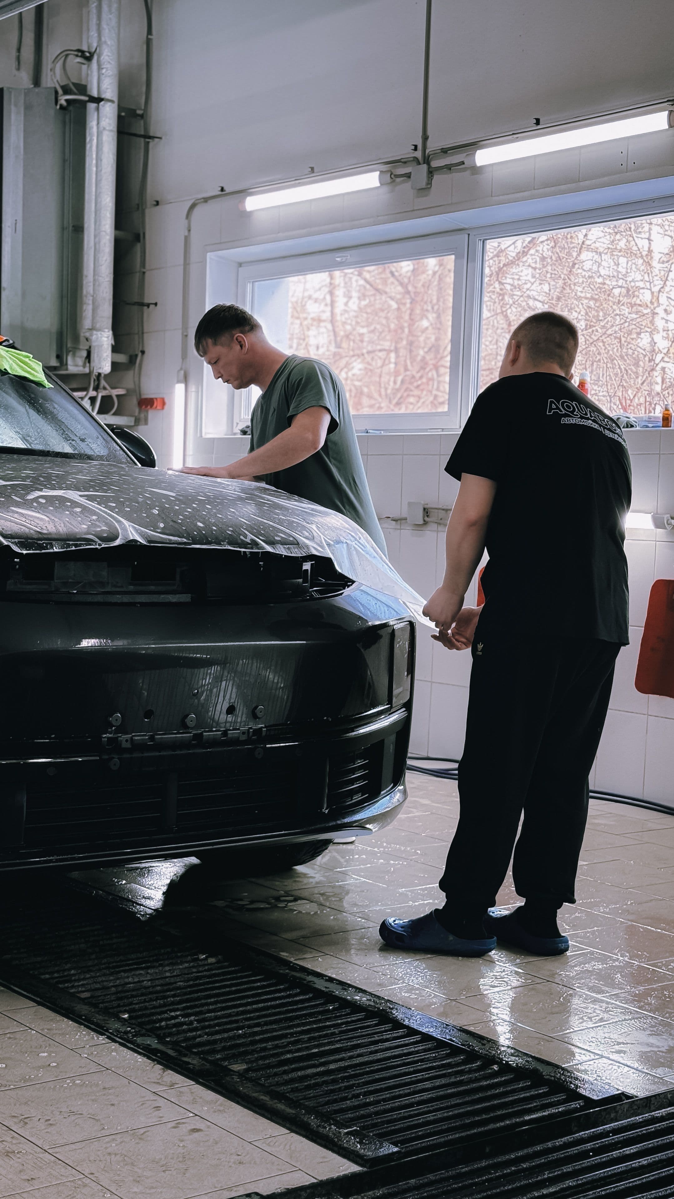 Specialists applying protection film in the GLOSS SHIELD studio
