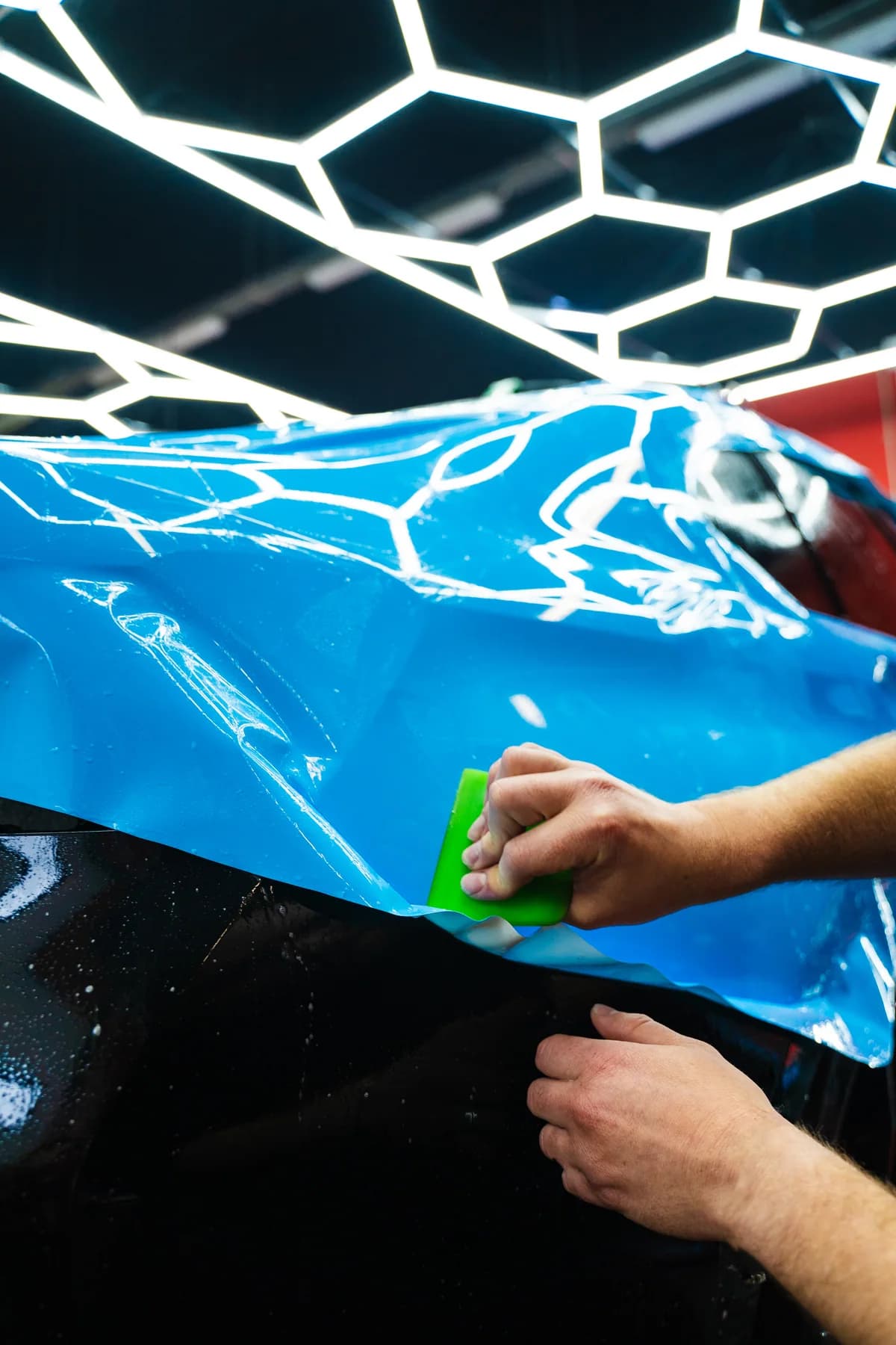 Blue film being carefully applied with a squeegee; an installation detail reference